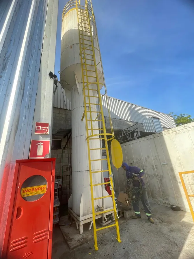 Linha de vida instalada em escada marinheiro de silo industrial, com trabalhador em operação